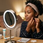 Dark-skinned African woman applying an overnight pimple patch to acne-prone skin during her nighttime skincare routine before heading to bed for the night.