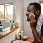 African man using an exfoliating pad on his face during a skincare routine for smoother, more even-looking skin texture in Nigeria.