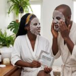 African woman applying a brightening sheet mask to reduce dark spots and hyperpigmentation during her skincare routine.